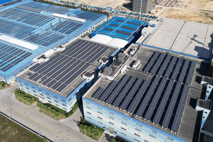 Industrial buildings with rooftop photovoltaic arrays and service equipment; contextual photograph.